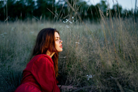 woman in the field lies on the grass in a red dress posingの写真素材