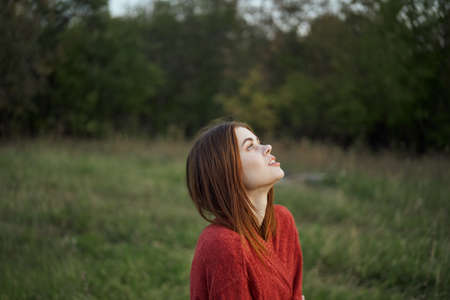 woman in a red sweater outdoors in the field nature restの写真素材