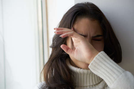 sad woman looking out the window close-upの写真素材