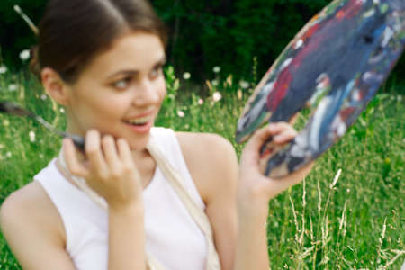 cheerful woman paints a picture palette nature landscapeの写真素材