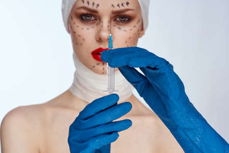 beautiful woman in blue gloves syringe in hands contour on the face lifting studio lifestyleの写真素材