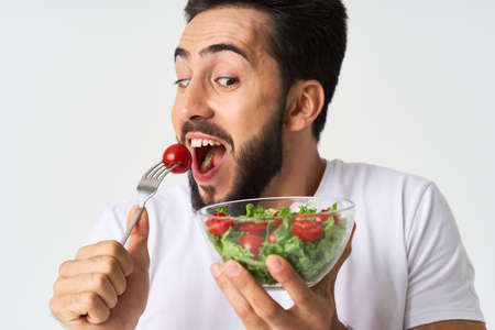 cheerful man in a white t-shirt a plate with salad vegetables dietの写真素材