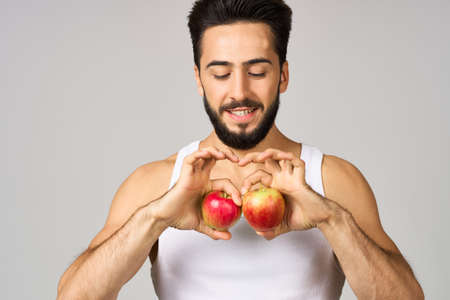a man in a white t-shirt apples in hands fruit healthy food studio lifestyleの写真素材