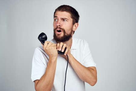 man with home phone in hands technology light background emotionsの写真素材