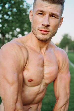sporty muscled man with naked torso in a workout parkの写真素材