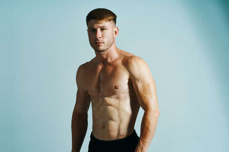 bodybuilder with muscular body posing press blue backgroundの写真素材