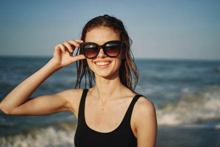 cheerful woman in black swimsuit sunglasses ocean travelの写真素材
