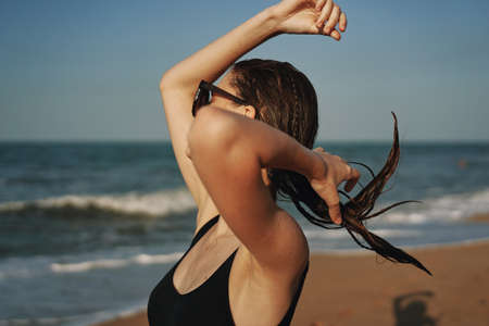 cheerful woman in black swimsuit sunglasses beach walk travelの写真素材