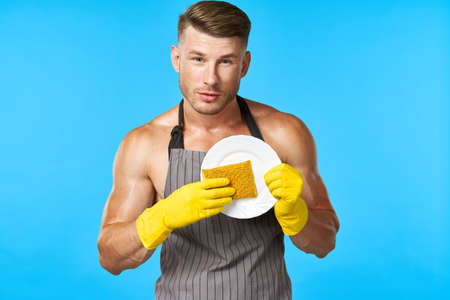 man in apron cleaning dishwashing blue backgroundの写真素材
