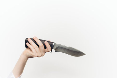 knife in hand close-up light background edged weaponの写真素材