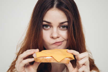 red-haired woman with a sandwich snack close-upの写真素材