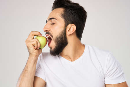 Cheerful man with apples in his hands in a white t-shirt fruitsの写真素材