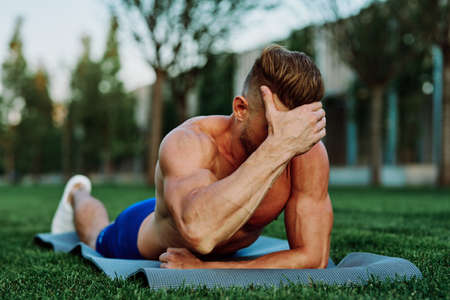 athletic man with pumped up muscular body in the park doing exerciseの写真素材