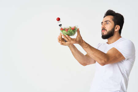 a man in a white t-shirt in a plate with salad a snack healthy foodの写真素材