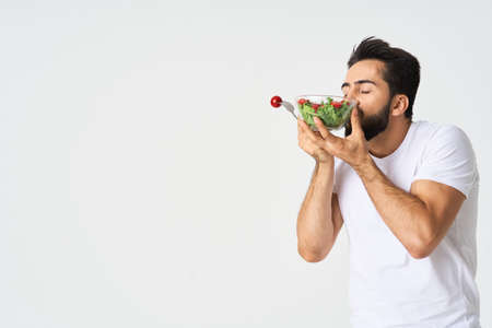 a man in a white t-shirt in a plate with salad a snack healthy foodの写真素材