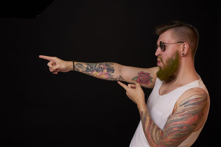 bearded man in white t-shirt with tattoos on his arms posing bully