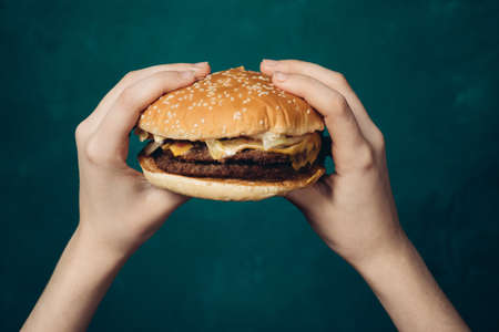 hamburger in hands close-up fast food green backgroundの写真素材