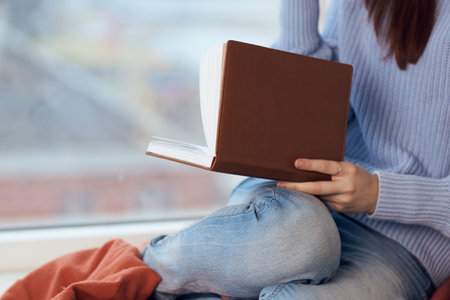 woman reading a book near the window with a cup of drink restの写真素材