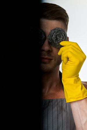 a man in a gray apron wearing rubber gloves cleaning washing