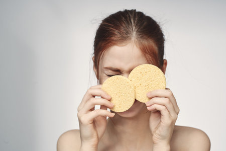 woman with a sponge in her hands bare shoulders skin care closeup