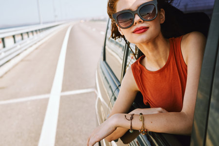 cheerful woman peeking out of the car window trip adventure lifestyleの写真素材