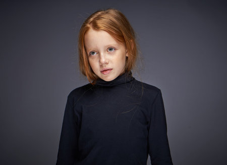 red-haired girl with freckles on her face in a black sweater posing