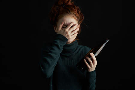 woman with bottle of alcohol bruises under eyes changes depression dark backgroundの写真素材