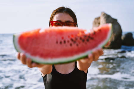 cheerful pretty woman in black swimsuit watermelon fashion travelの写真素材