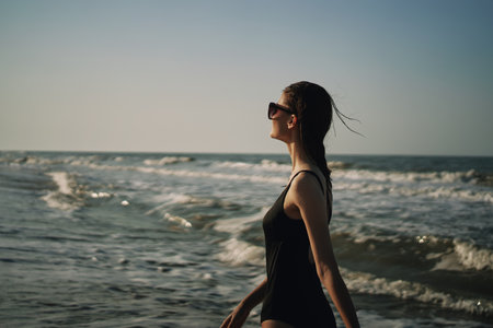 woman in black swimsuit walking on the beach ocean summerの写真素材