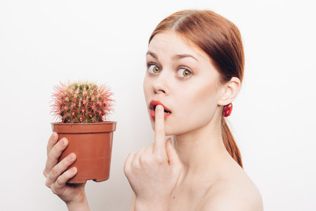 woman with bare shoulders with a cactus in her handsの写真素材
