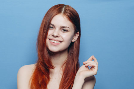 attractive woman with bare shoulders red hair close-up blue background