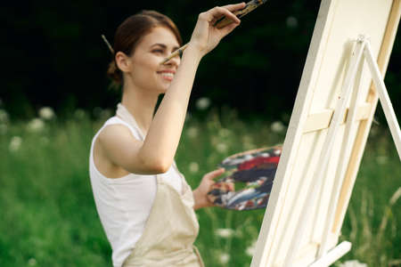 cheerful woman artist painting a picture outdoors creative artの写真素材