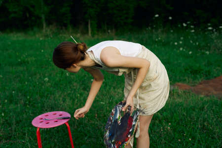 Woman in white dress with palette of paints on nature art drawingの写真素材