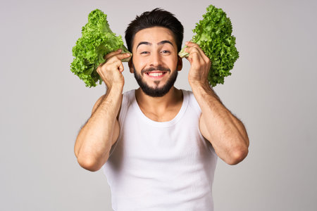 Cheerful man lettuce leaves healthy food posing