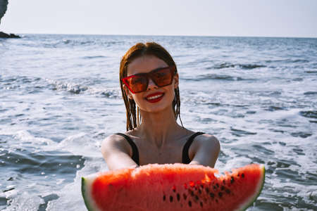 pretty woman in a black swimsuit with a watermelon in her hands summer Oceanの写真素材