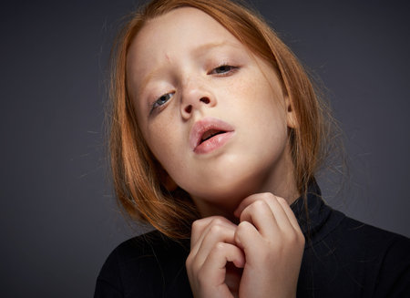 red-haired girl with freckles on her face in a black sweater posing