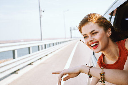 cheerful woman peeking out of the car window trip road travel