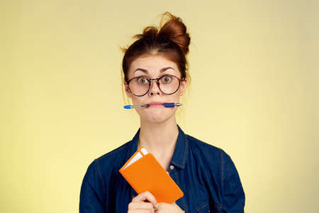 woman student with glasses notepad with pen yellow backgroundの写真素材