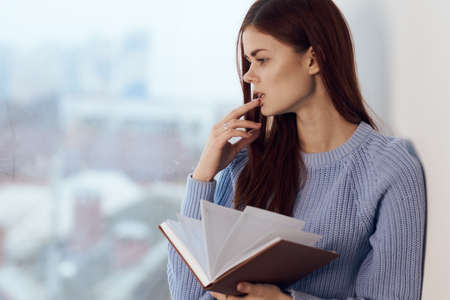 woman reading a book near the window with a cup of drink restの写真素材