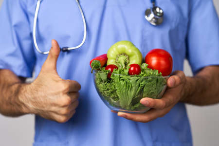 birth bearded male doctor plate with vegetables healthy food treatment caloriesの写真素材