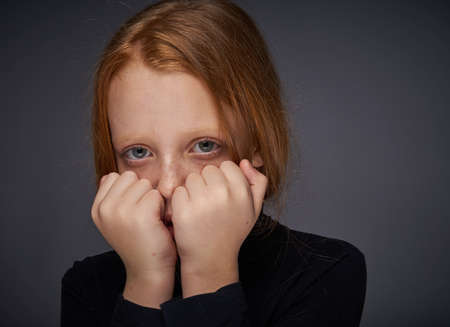 red-haired girl with freckles on her face in a black sweater posingの写真素材