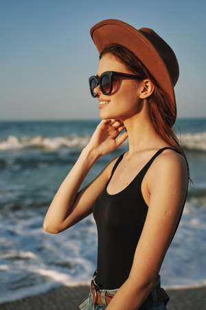 cheerful woman in sunglasses and a hat by the ocean walk summerの写真素材