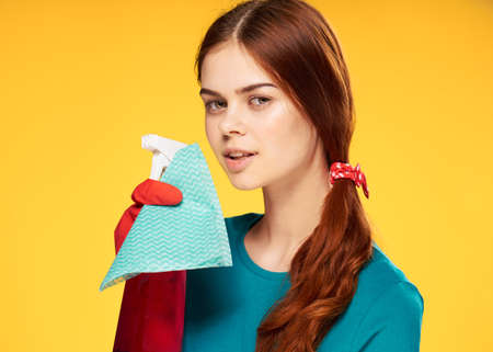 woman in rubber gloves detergent cleaning housework yellow backgroundの写真素材