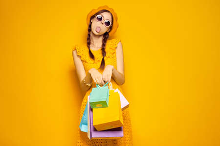 cheerful woman with multicolored bags posing yellow backgroundの写真素材