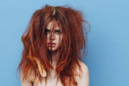 woman with red hair comb care blue backgroundの写真素材