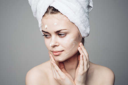 woman with bare shoulders towel on head face cream skin careの写真素材