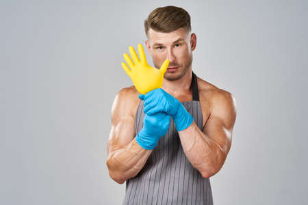 pumped up man in apron rubber gloves cleaning houseworkの写真素材