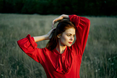cute red-haired woman in red dress in field nature summerの写真素材