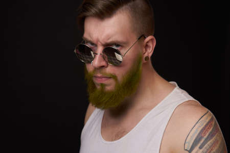 handsome man with tattoos on his arms fashion sunglasses dark backgroundの写真素材