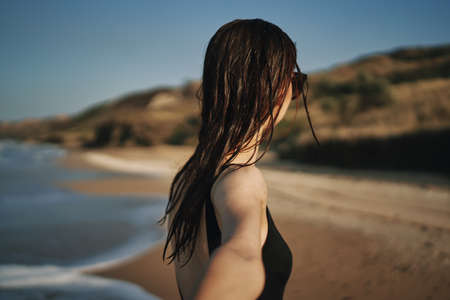 cheerful woman in a black swimsuit walking along the beach tropics summerの写真素材